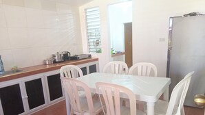 Een keuken met witte kastjes, een aanrecht en een eettafel met vier stoelen.