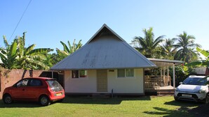 A small house with a sloped roof, a front porch, and a garage. - FARE AT MARIE LOU (Papetoai Moorea)