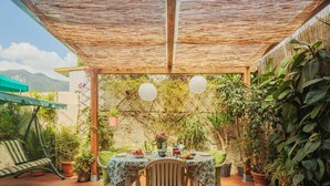 A covered patio with a table set for two, surrounded by potted plants and a bamboo trellis. - Beautiful  villa for 4 people with WIFI, TV and terrace (Massa)