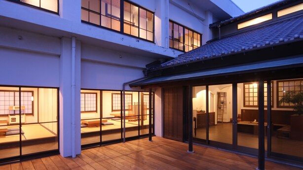 Un immeuble à plusieurs étages doté d’une terrasse en bois et de portes-fenêtres coulissantes qui donnent sur un intérieur de style traditionnel.