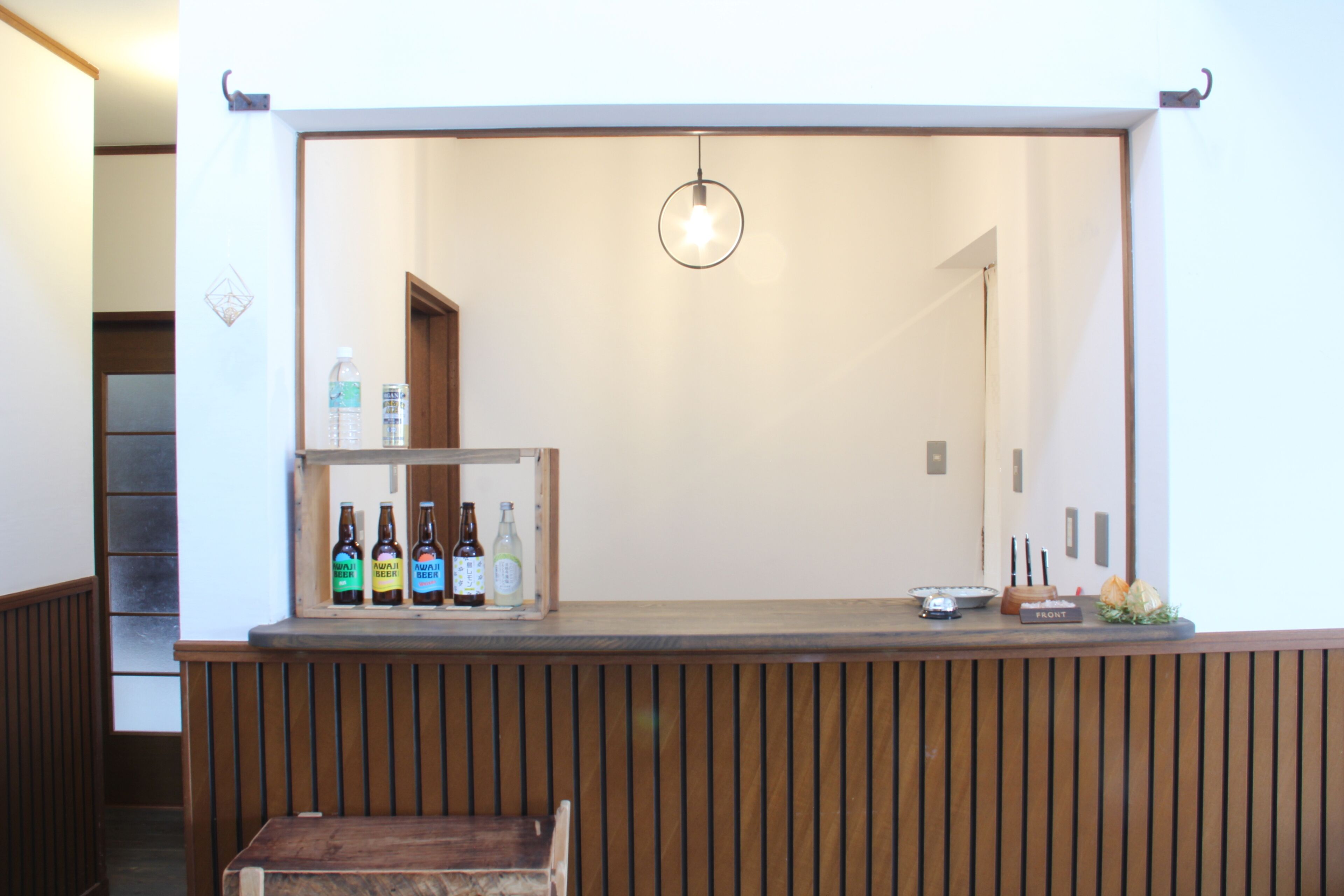 Un comptoir d’accueil avec un revêtement en bois, un luminaire suspendu et une étagère contenant des boissons en bouteille.