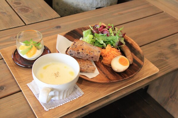 Una mesa de madera con comida que incluye sopa, pan, ensalada y un huevo duro.