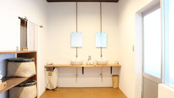 Een moderne badkamer met twee wastafels, houten planken en een groot raam.
