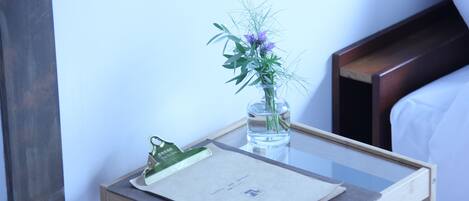 A small wooden side table with a clipboard, a glass vase with flowers, and a water bottle.