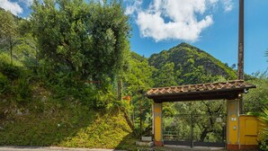 A paved road leading to a gated entrance with a tiled roof structure.