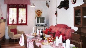 A dining area with a table set for four, a television, and a sofa.