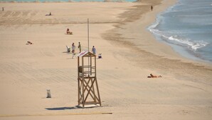 A beach with a lifeguard tower, sandy shore, and calm sea.