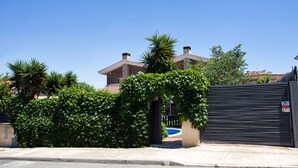 A residential property with a gated entrance, a swimming pool, and a clear blue sky.
