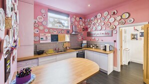 Une cuisine aux murs roses, dotée d’un plan de travail en bois et ornée de diverses assiettes décoratives accrochées au mur.