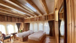 Un dormitorio de cabaña de madera con dos camas, un espejo grande y suelo de madera.