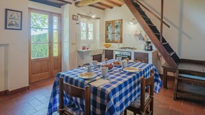 Une cuisine rustique avec une nappe à carreaux, des poutres en bois et un escalier.