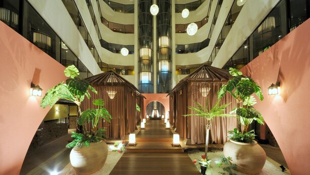 A hotel lobby with a central wooden pathway, potted plants, and a modern interior design. - Hotel Sol - Adults Only (Fukuoka)