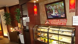 A cafe with a sign reading "CAFE de SOL" and a display case with various pastries and fruits. - Hotel Sol - Adults Only (Fukuoka)