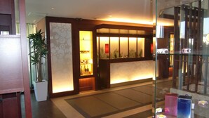 A reception area with a reception desk, a potted plant, and a glass display case with items. - Hotel Sol - Adults Only (Fukuoka)