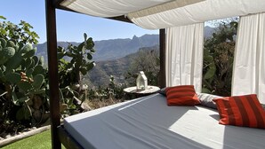 Un lit à baldaquin, une table de chevet avec une lampe et une vue sur les montagnes.