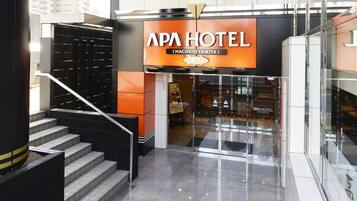 Enter the APA Hotel, where a sleek glass door and staircase welcome you.