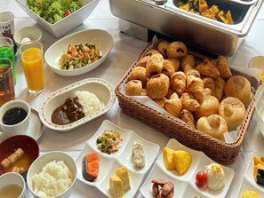 Ein Buffet mit verschiedenen Speisen, darunter Reis, Fleisch, Gemüse und Gebäck.