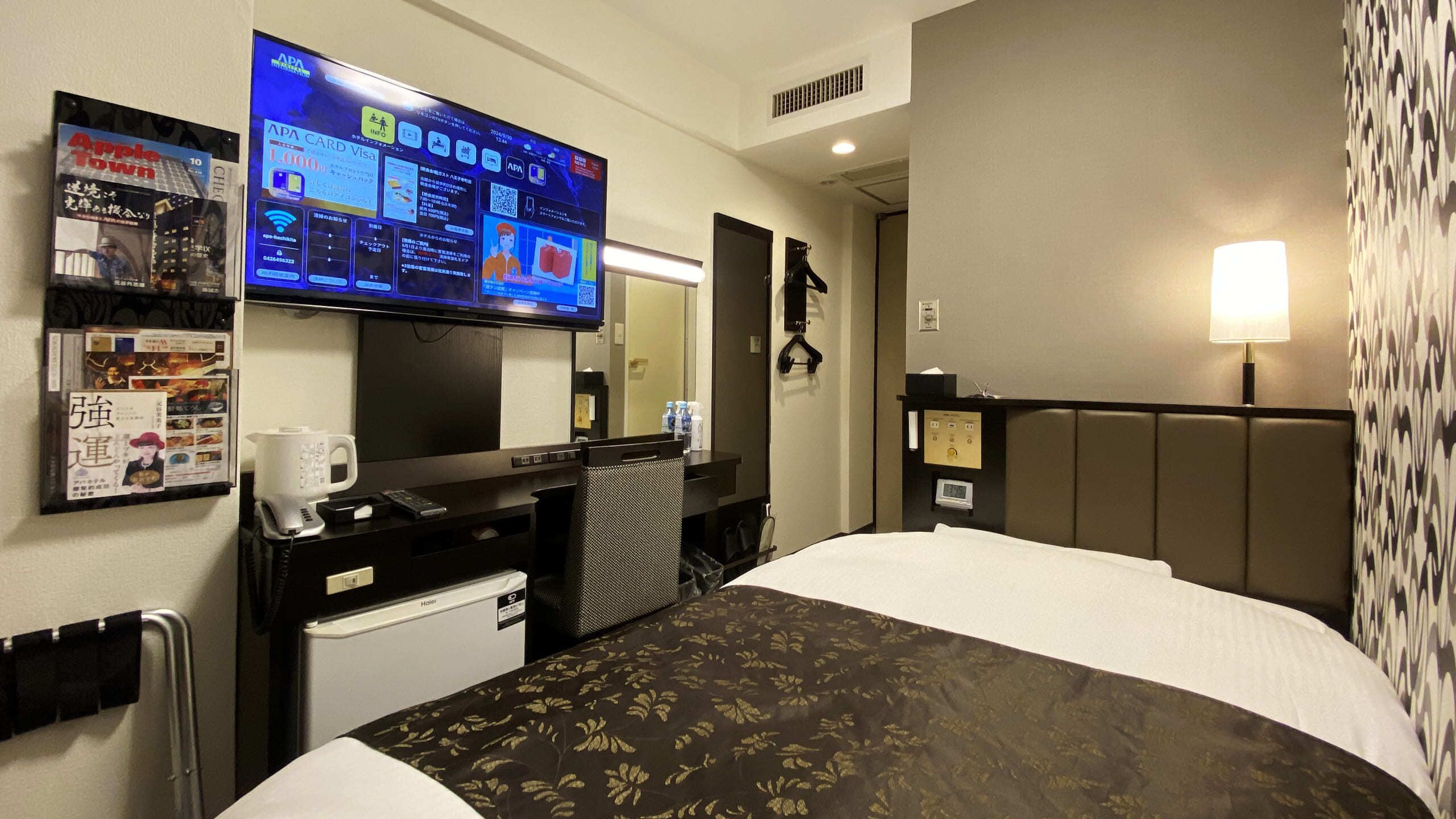 Une chambre d’hôtel équipée d’un lit, d’un bureau avec un ordinateur, d’une télévision et d’un mini-bar.