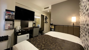 A hotel room with a bed, a desk with a computer, a television, and a mirror.