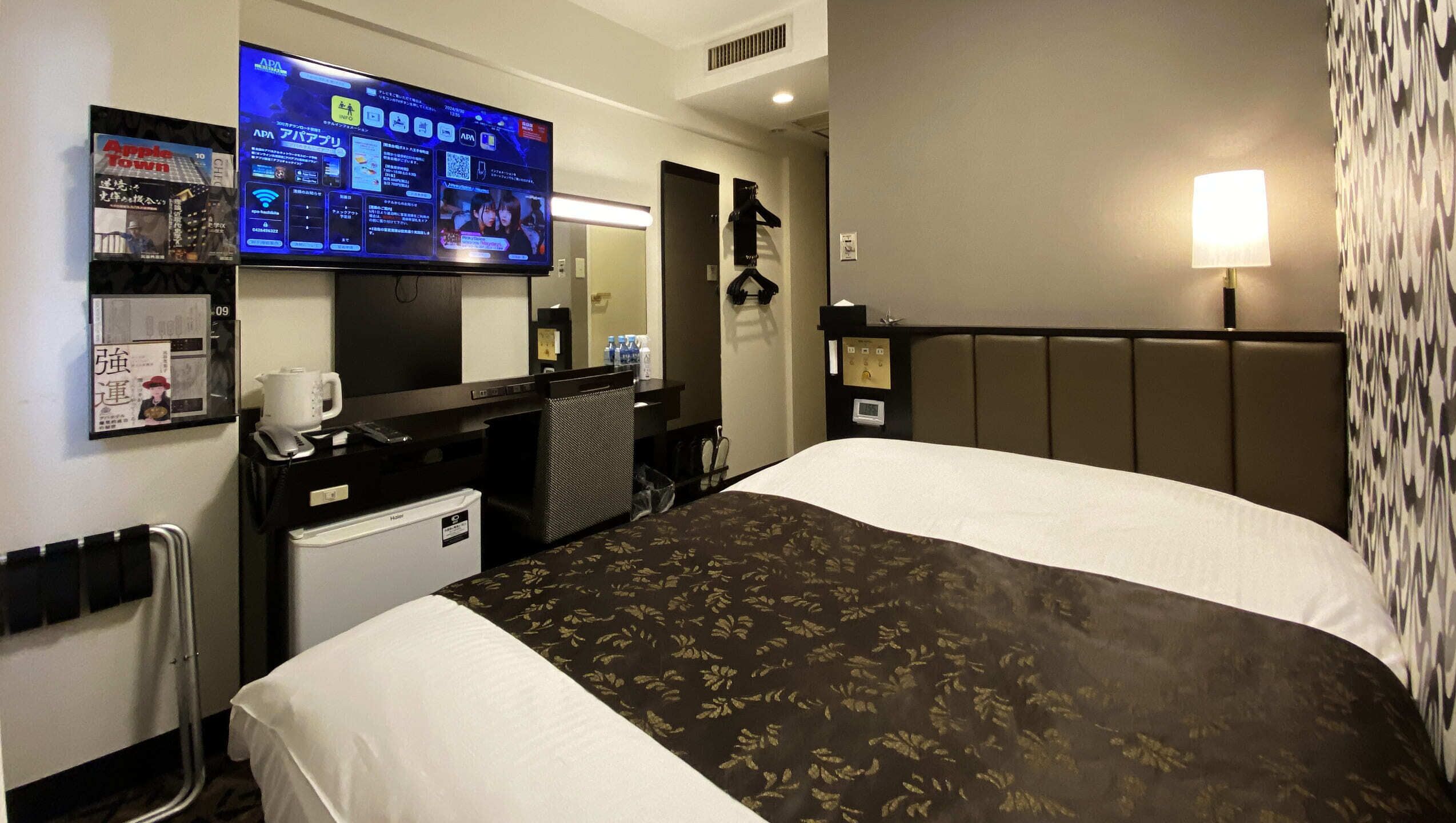 Ein Hotelzimmer mit Bett, Schreibtisch, Computer, Fernseher und einer Minibar.