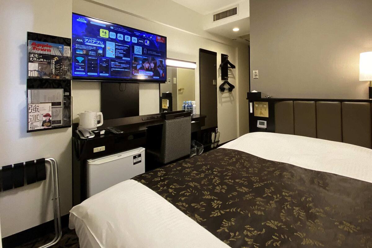 Une chambre d’hôtel équipée d’un lit, d’un bureau avec un ordinateur, d’une télévision et d’un mini-bar.