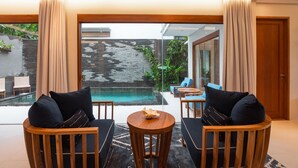 Un salon moderne avec vue sur la piscine, doté de meubles en bois et d’une grande porte vitrée donnant sur l’extérieur.