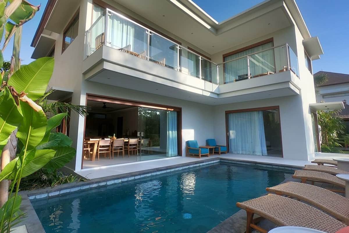 Una casa moderna de dos pisos con piscina, zona de estar exterior y balcón.