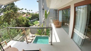 Un balcon moderne avec une rambarde en verre, une piscine et du mobilier d’extérieur.
