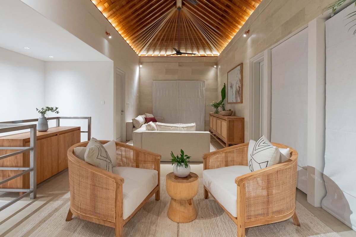 Un dormitorio moderno con techo de madera, cama, sofá y una mesita de noche.