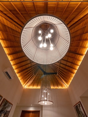 Un plafond de forme circulaire agrémenté d’un luminaire central et d’une suspension décorative.
