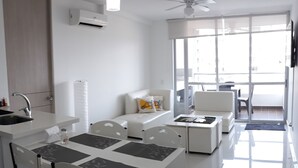 A modern kitchen with a dining area, white furniture, and a large window offering a view of the city. - Comfort, NATURE, REST AND FUN WITH THE FAMILY (RICAURTE CUNDINAMARCA)