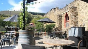 An outdoor seating area with stone walls, tables, and umbrellas. - Clyde Gem (Clyde)