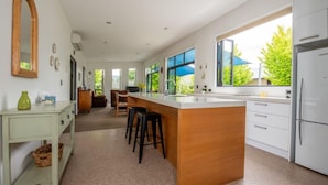 A modern kitchen with a large island, white cabinetry, and a view of the outdoors. - Clyde Gem (Clyde)