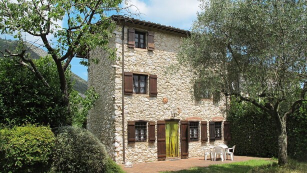 Un bâtiment en pierre doté de nombreuses fenêtres et d’un patio aménagé avec des sièges extérieurs.