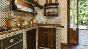 Une cuisine avec des carreaux décoratifs, des armoires en bois et une cuisinière à gaz.