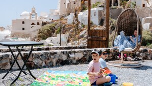 Ein Strand mit einem Kind, das auf einer Matte spielt, einem Korbstuhl und einem Tisch.