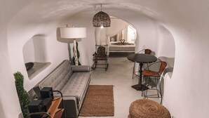 Ein modernes Interieur mit einer Couch, einem Esstisch, Stühlen, einer Lampe und einer Zimmerpflanze.