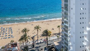 A beach with palm trees, a building with balconies, and a clear blue sea. - Acintur 13-A (Benidorm)