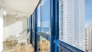 A balcony with a view of tall buildings, a ceiling fan, and white plastic chairs. - Acintur 13-A (Benidorm)