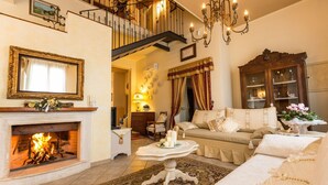 A cozy living room with a fireplace, a sofa set, a dining table, and a staircase leading to an upper floor. - Private Villa with WIFI, A/C, private pool, TV, patio, panoramic view, close to San Gimignano (Iano)