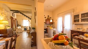 A dining area with a table set for two, a kitchen in the background, and a staircase leading to an upper floor. - Private Villa with WIFI, A/C, private pool, TV, patio, panoramic view, close to San Gimignano (Iano)