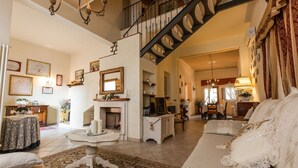 A spacious living room with a fireplace, a staircase, and a dining area. - Private Villa with WIFI, A/C, private pool, TV, patio, panoramic view, close to San Gimignano (Iano)