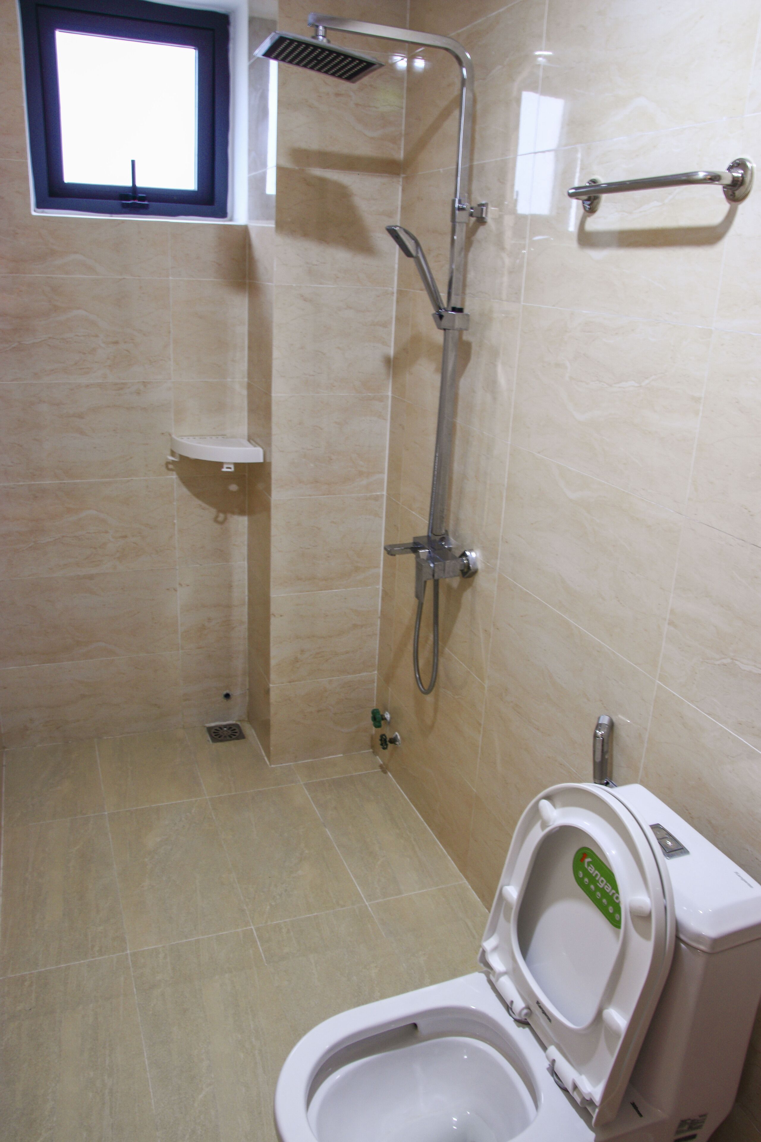 A bathroom with a toilet, a shower, and a window.