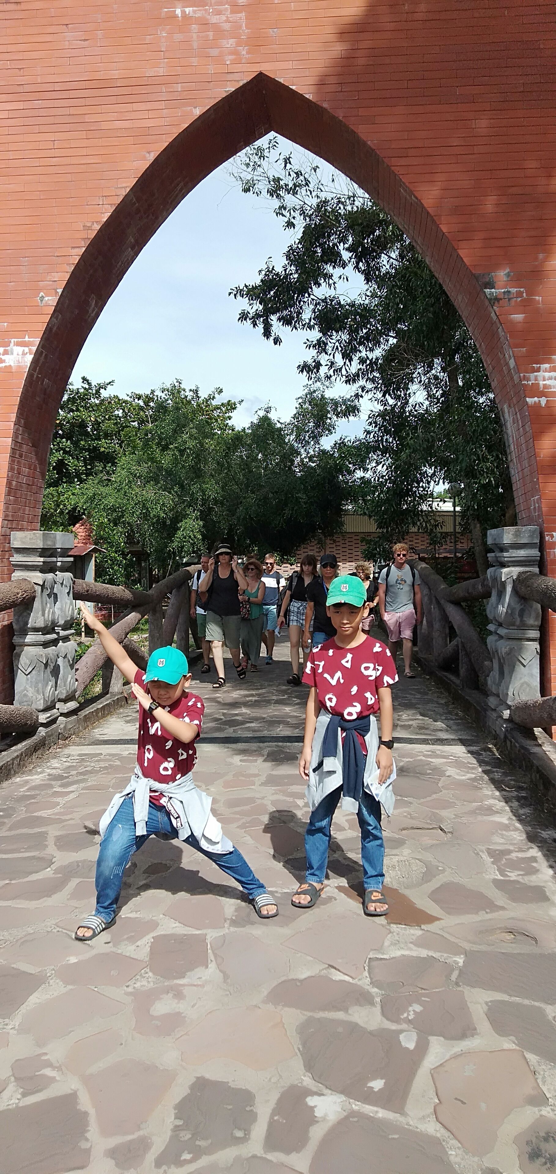 Two children performing a dance under a brick archway.