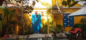 Un patio colorido con macetas, una puerta azul y un letrero que dice 'Hello'.