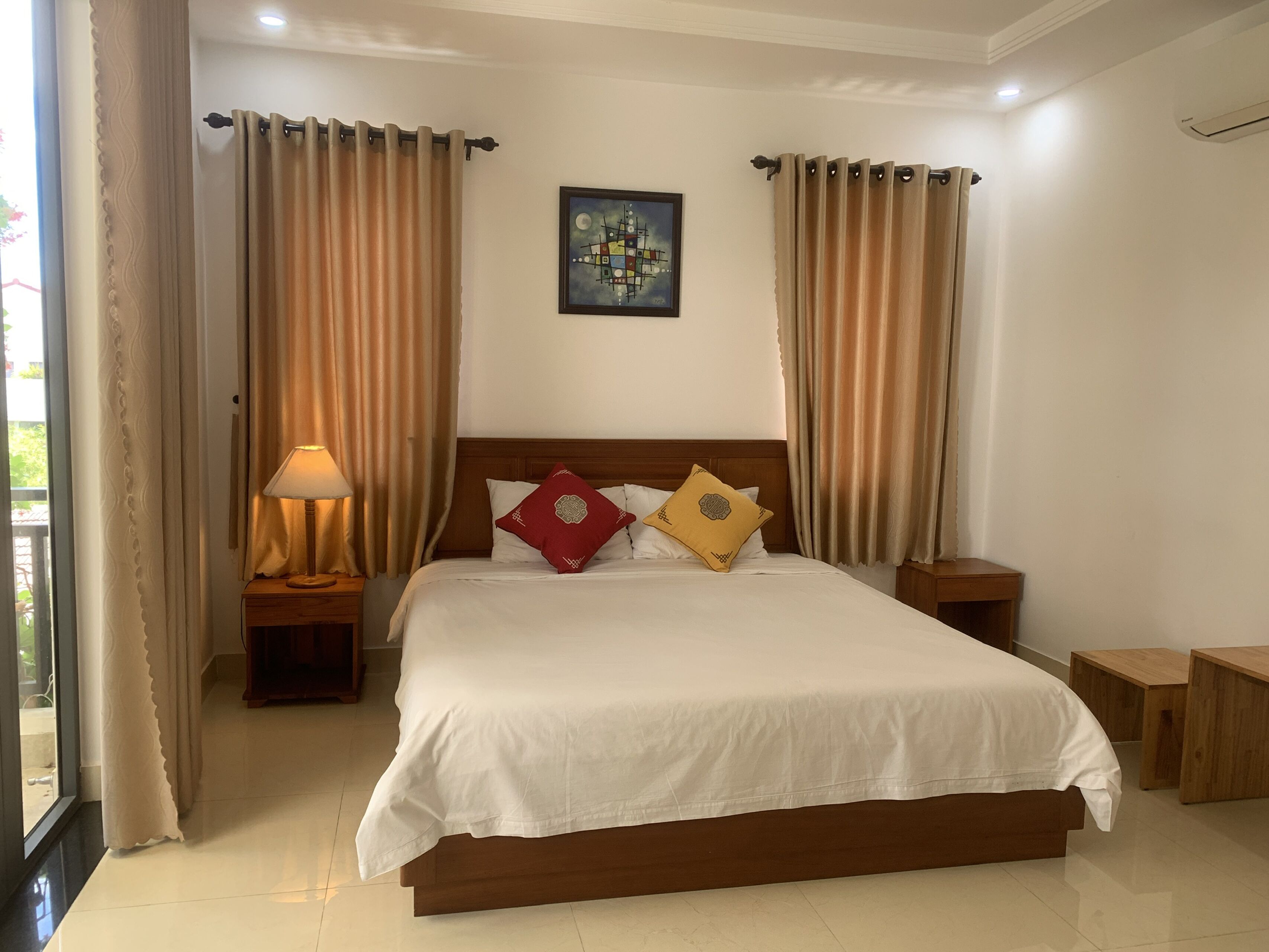 A hotel room with a large bed, two nightstands, a lamp, and a painting on the wall.