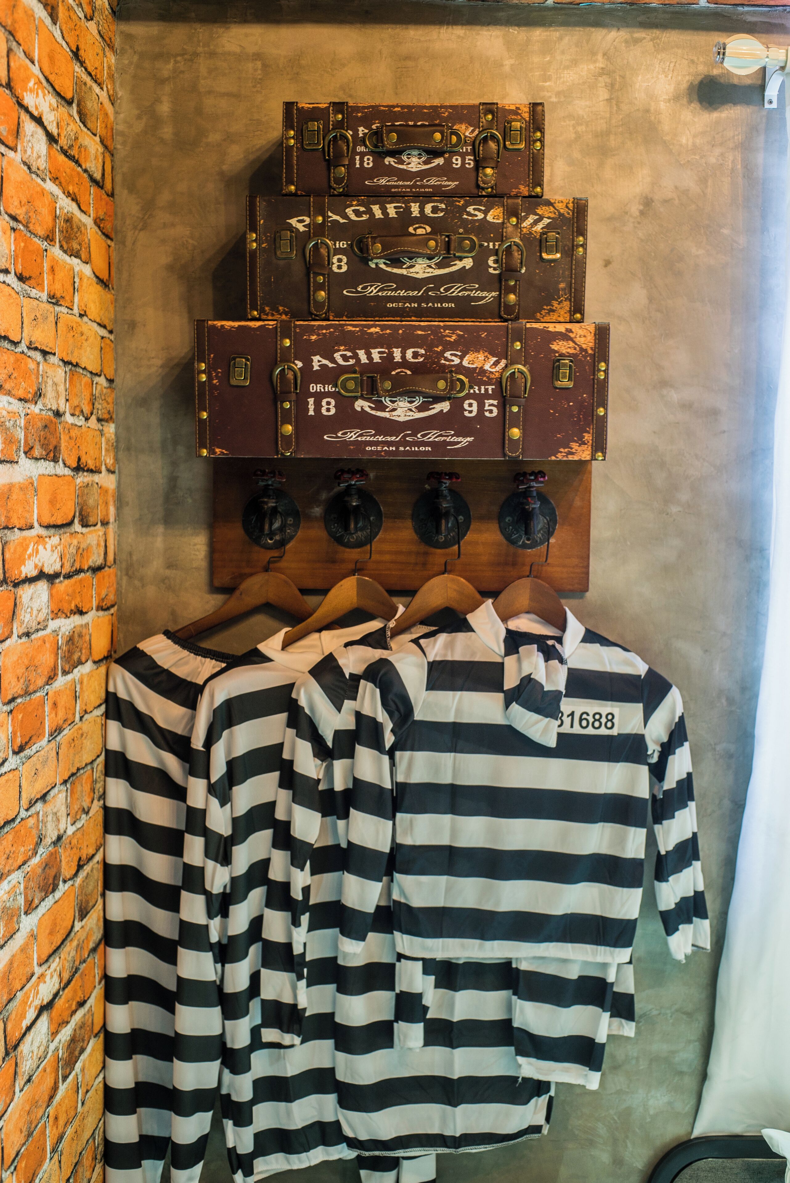 Una pared con maletas antiguas y un perchero con camisas a rayas.