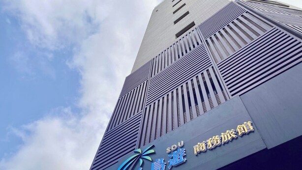A tall building with a modern architectural design, featuring a prominent logo and signage for 'SOU' and 'Brand Travel'. - Hexing Hotel (Magong)