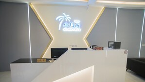 A reception desk with a modern design, featuring a logo and a sign indicating it is for employees only. - Hexing Hotel (Magong)
