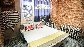 A room with a bed, striped shirts, and a brick wall.